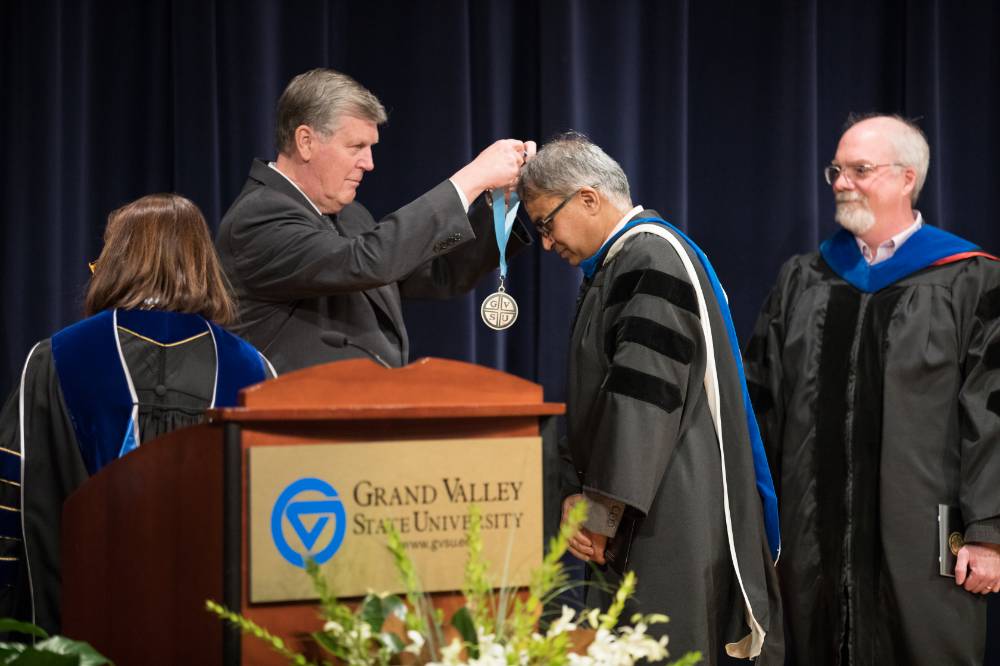 President Emeritus Haas placing a medallion over a faculty member on stage.